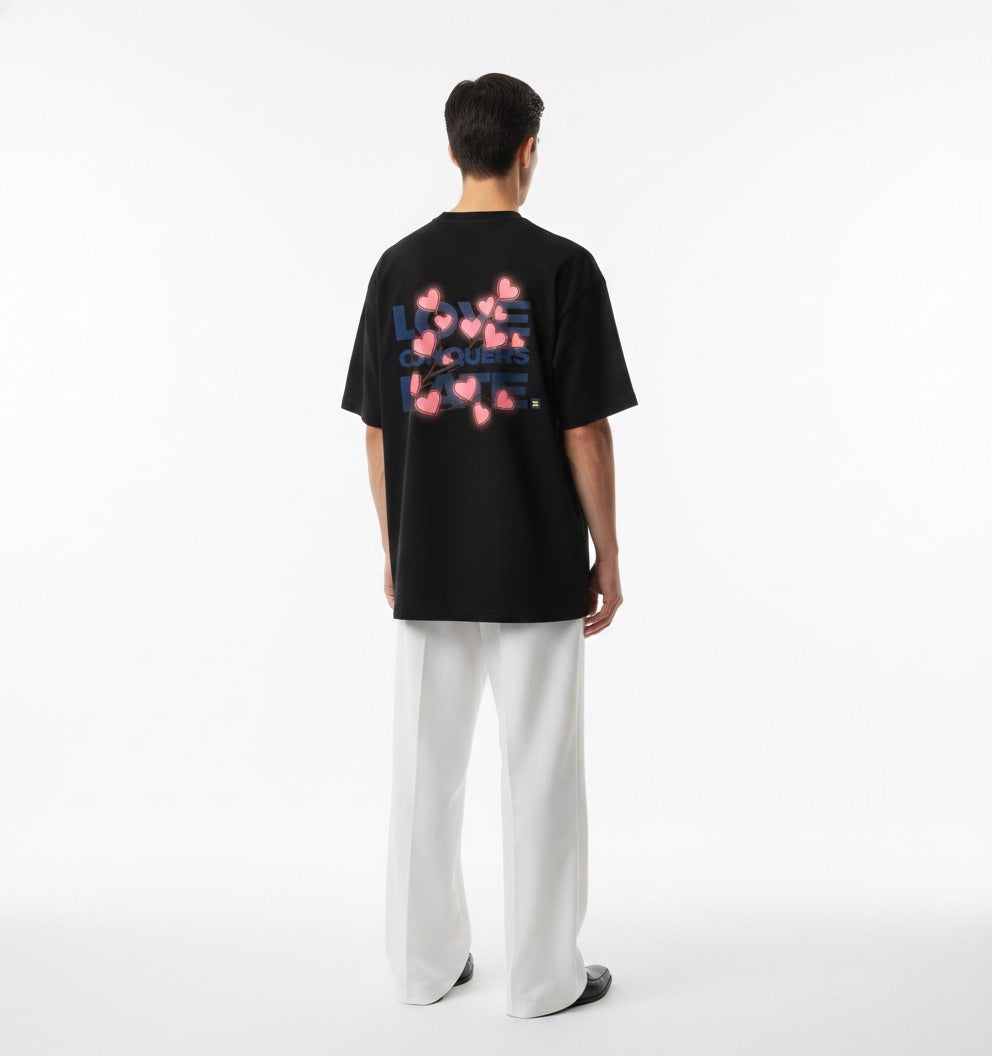 Person wearing a white t-shirt with 'Love Conquers Hate' text and floral design on the back.