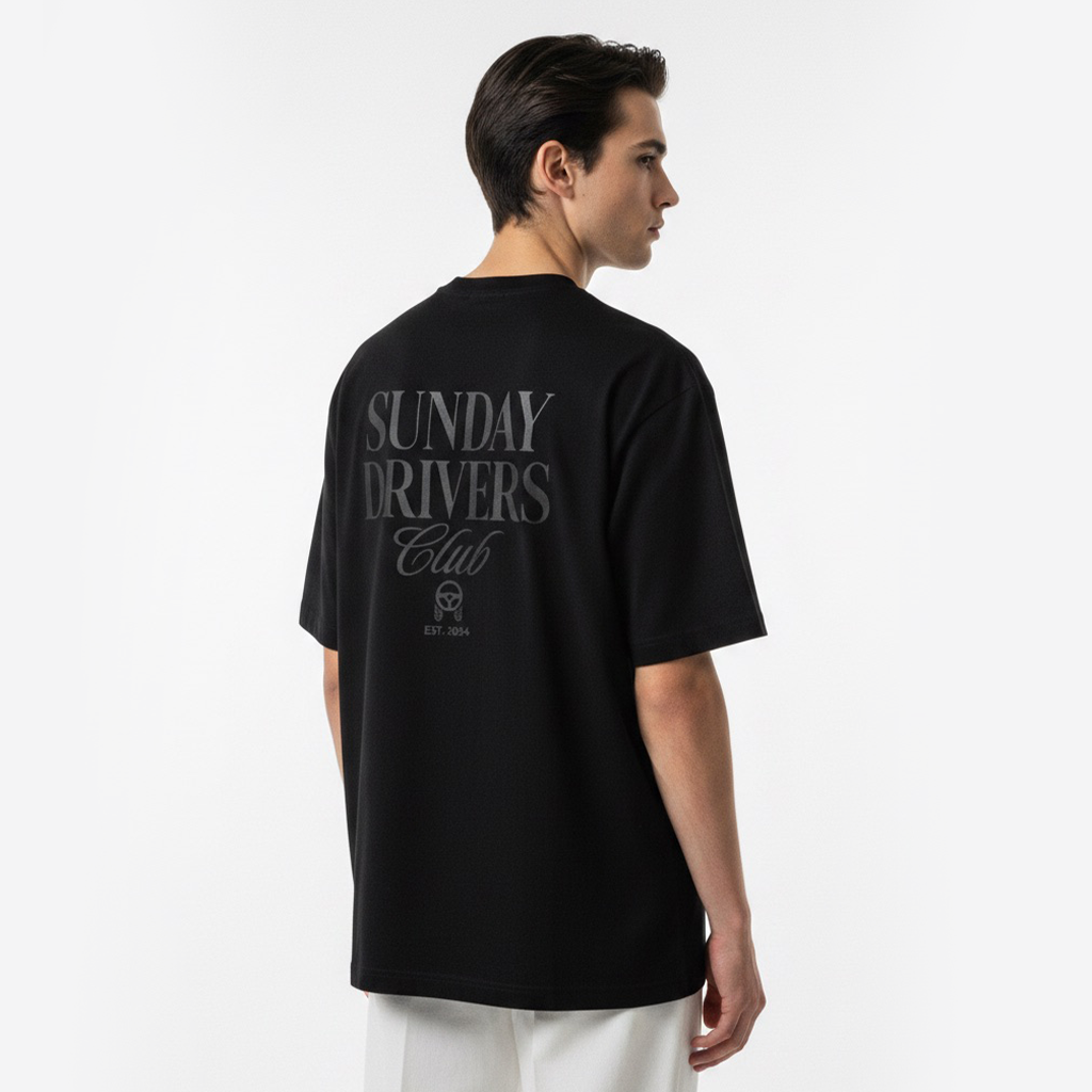 Person wearing a white t-shirt with 'Sunday Drivers Club' text on the back, standing against a plain background.