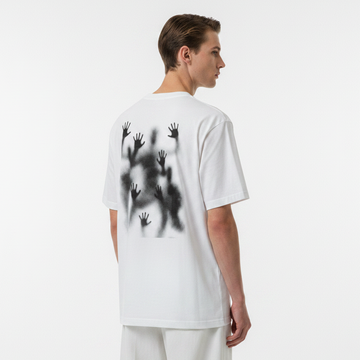 Person wearing a white t-shirt with black handprints on the back against a plain background