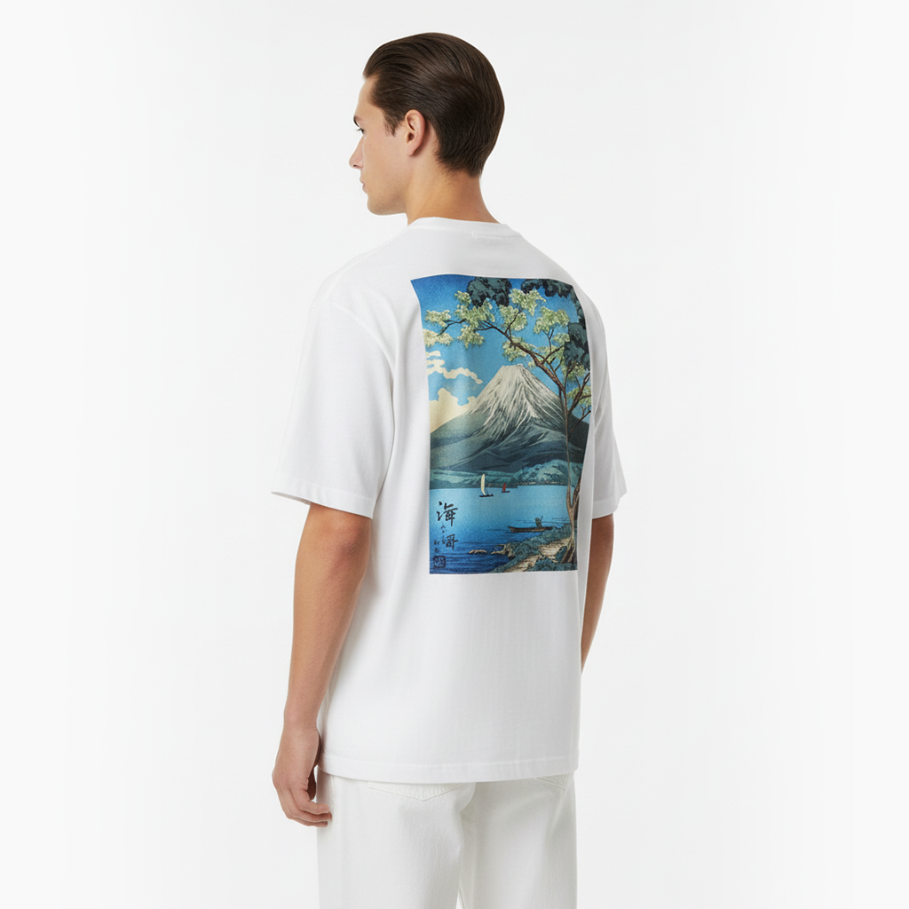 Person wearing a white t-shirt with a scenic graphic on the back, standing against a plain background.
