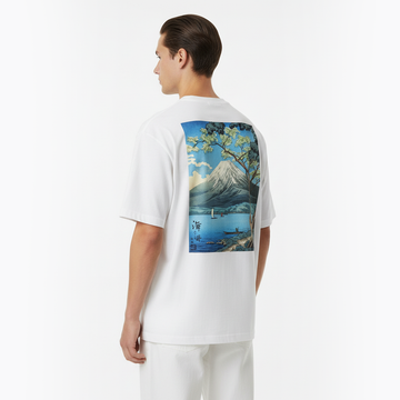 Person wearing a white t-shirt with a scenic graphic on the back, standing against a plain background.