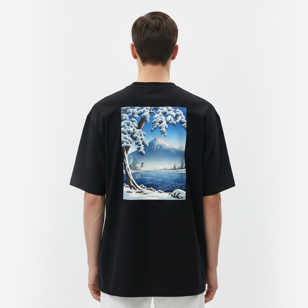 Person wearing a white t-shirt with a scenic print on the back, standing against a plain background