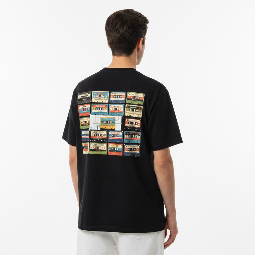 Person wearing a white t-shirt with cassette tape design on the back against a plain background