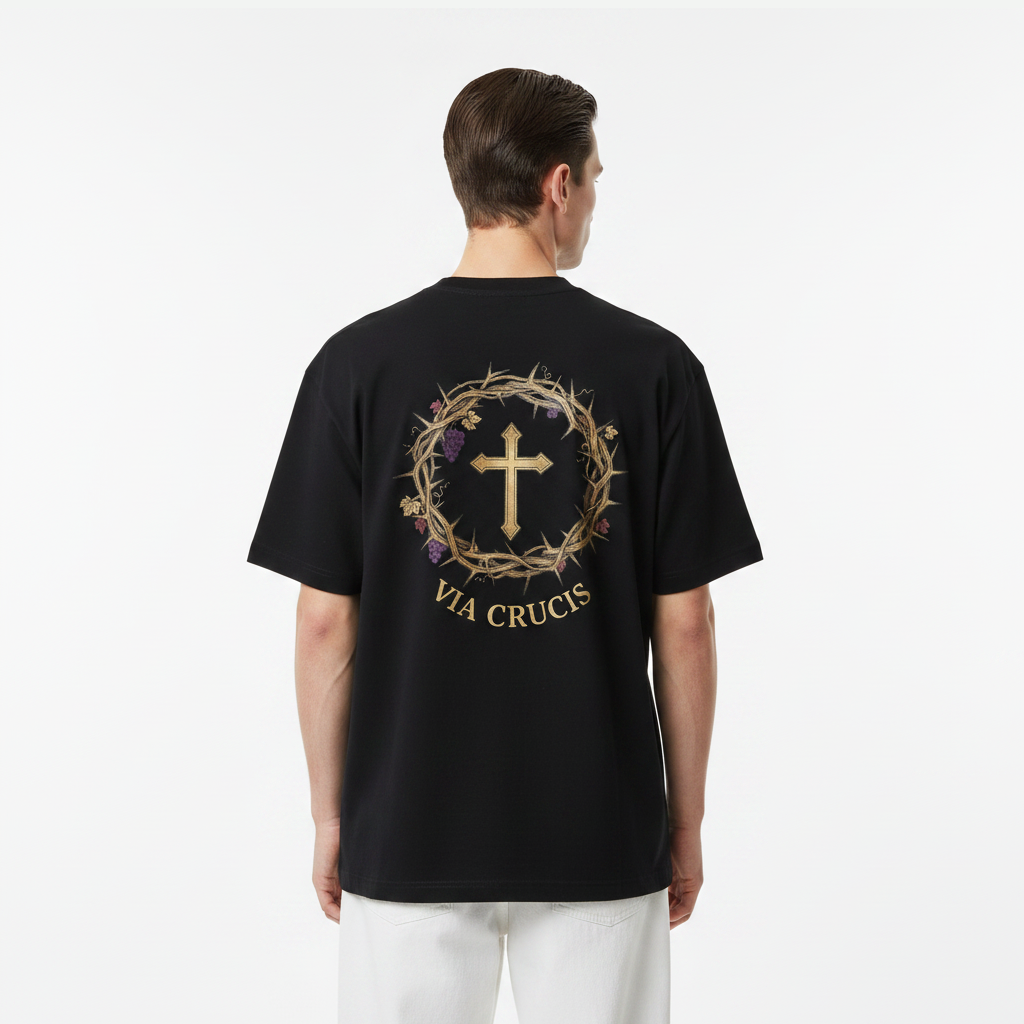 Person wearing a black t-shirt with a 'Via Crucis' design on the back, standing against a white background.