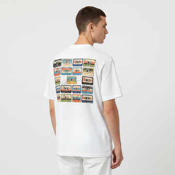 Person wearing a white t-shirt with cassette tape design on the back against a plain background